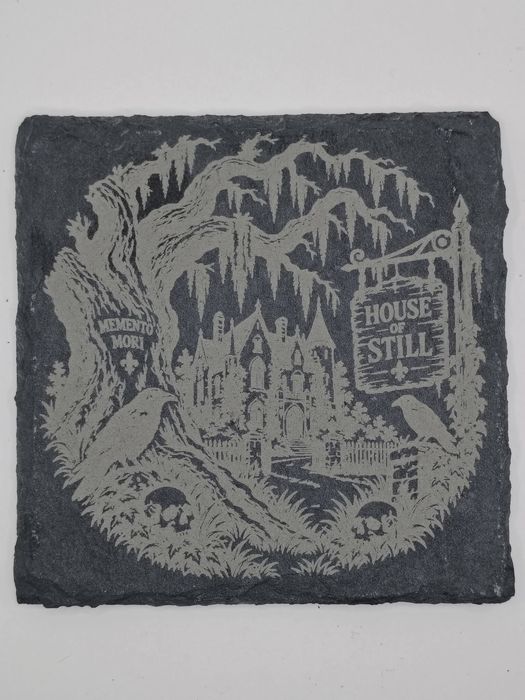 Slate coaster engraved with a Gothic house under moss-draped oaks and a House of Still sign