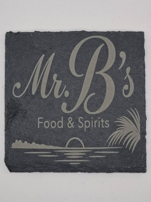Slate coaster engraved with the Mr. B&rsquo;s Food and Spirits logo and a waterfront sunset