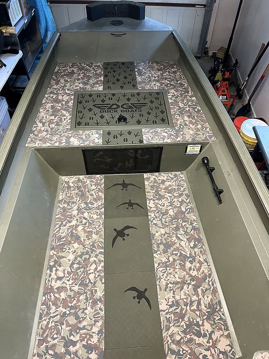 Duck boat deck with camo EVA flooring engraved with flying ducks, a retriever, and a wood duck